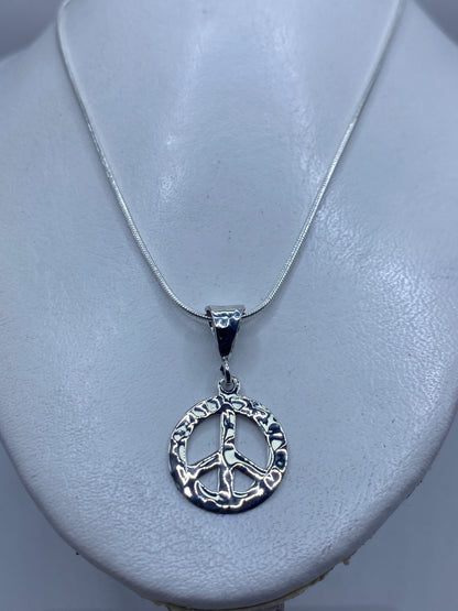 Detalle del símbolo de paz en relieve, repujado a mano en plata .925