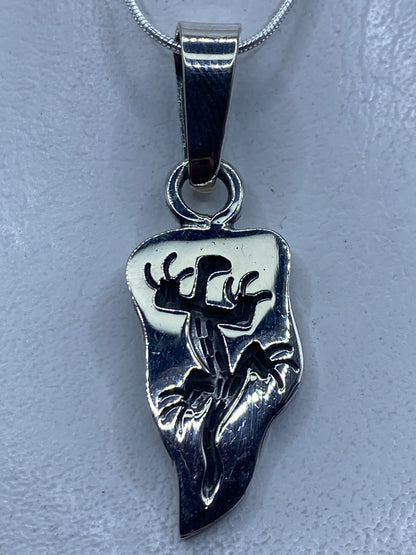 Dije de plata con motivo prehispánico en forma de guerrero, colgando de cadena plateada