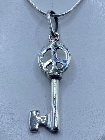Dije llave de plata .925 en calado con símbolo de paz, 4.7 cm, colgando de cadena plateada