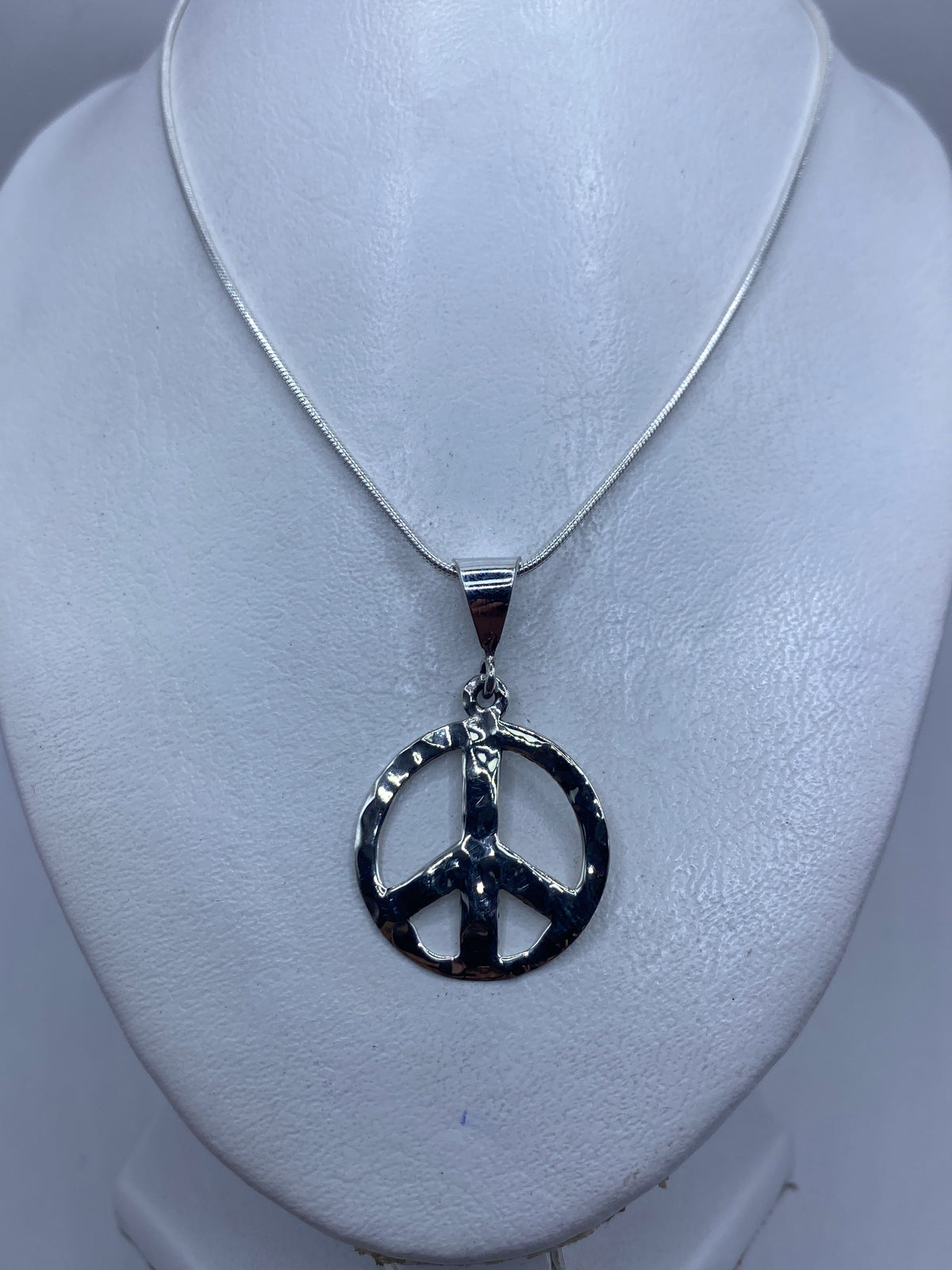 Detalle del repujado a mano en la superficie del dije de paz