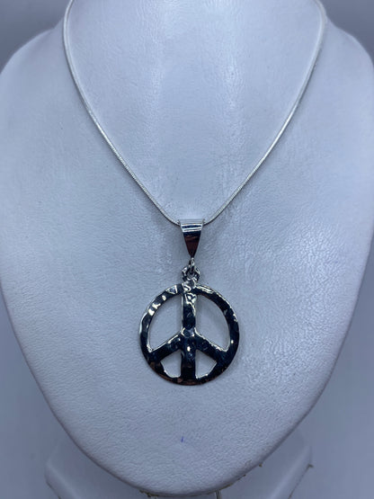 Detalle del repujado a mano en la superficie del dije de paz