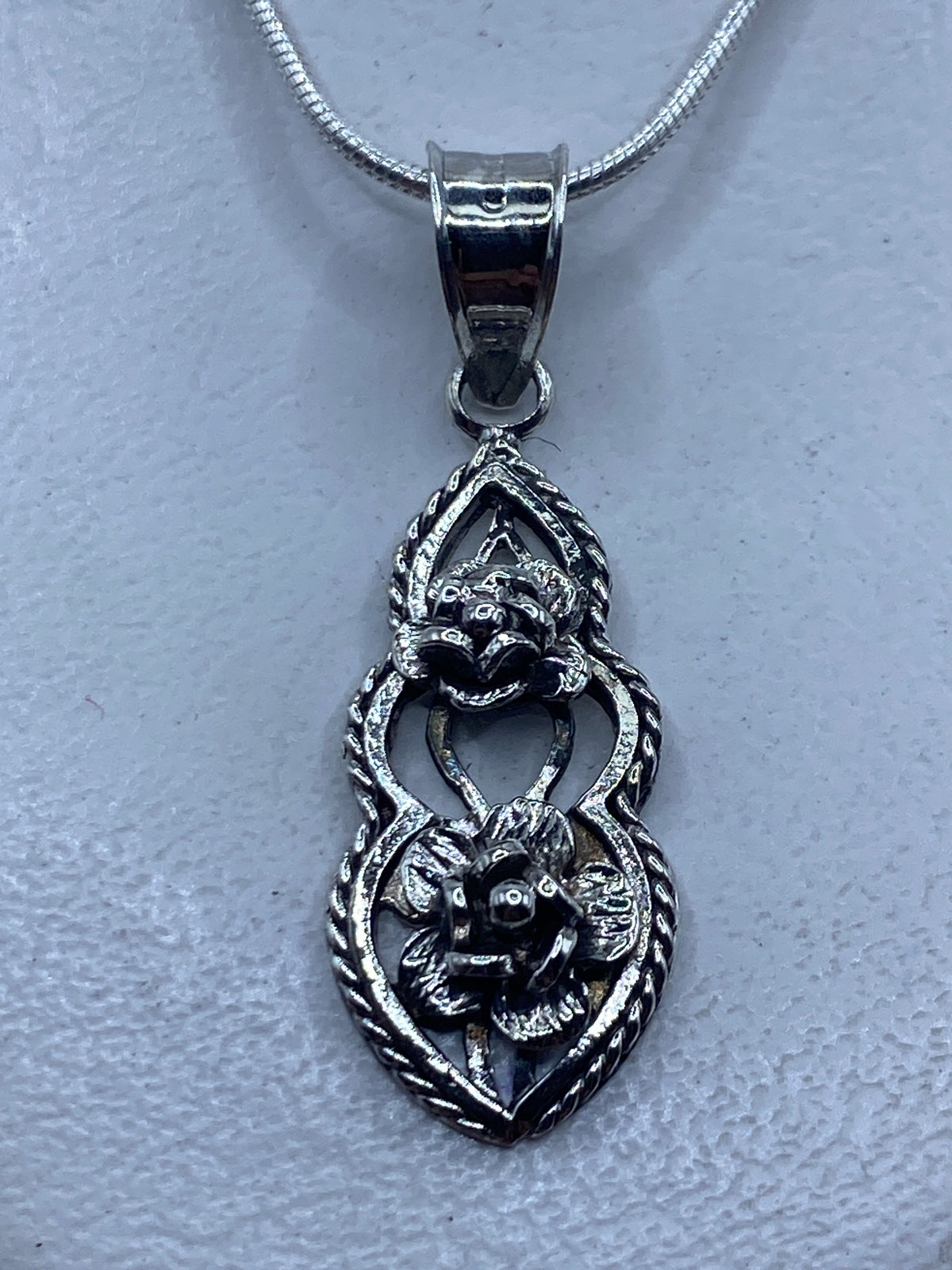 Dije de plata prehispánico de 4 cm con motivos tallados en relieve