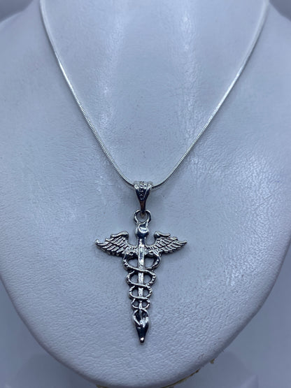 Dije Caduceo sobre pecho, vista de cómo se ve puesto — 4.4 cm de largo