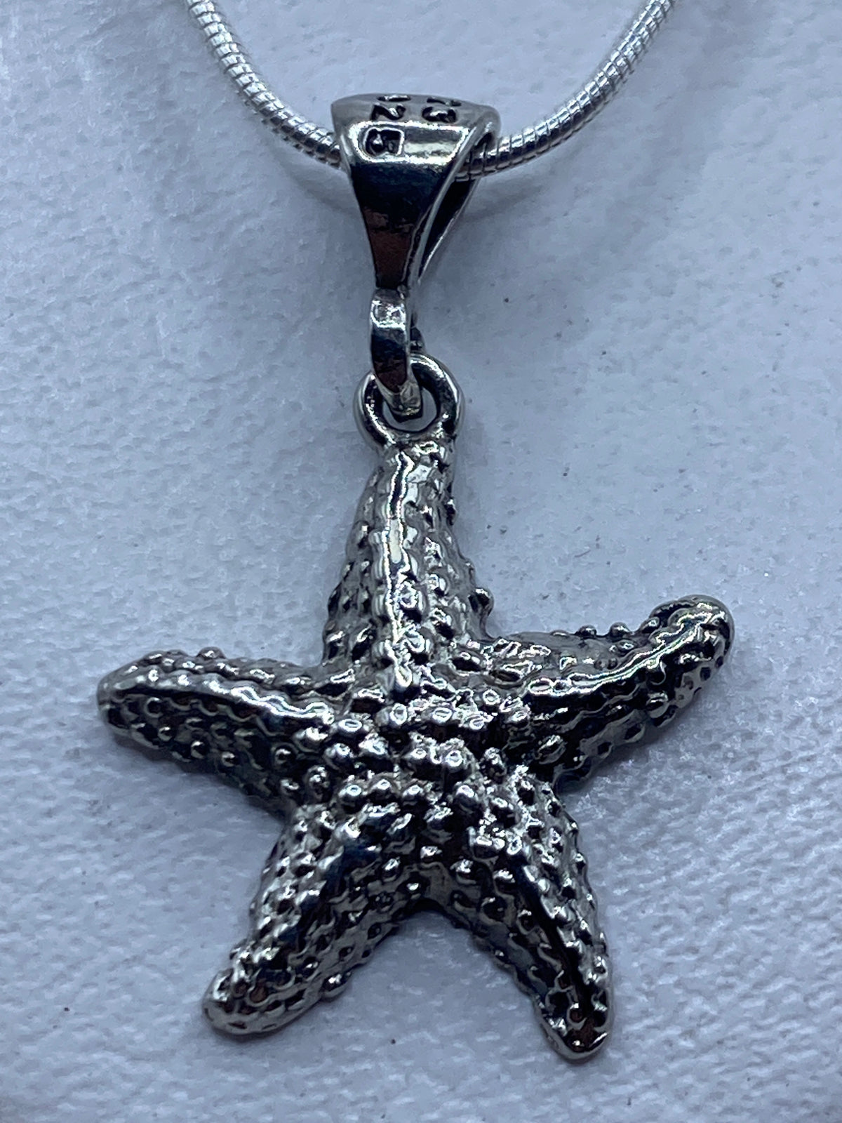 Dije estrella de mar en plata .925 con técnica de granulado, visto de frente mostrando la textura de bolitas soldadas