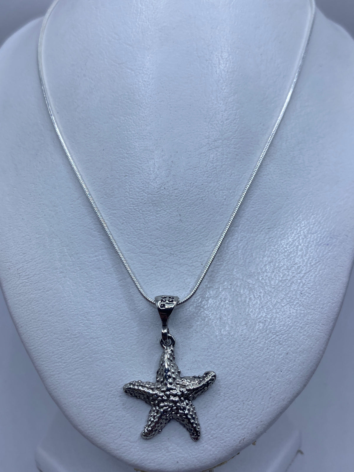 Detalle cercano del dije estrella de mar mostrando las bolitas de plata soldadas a mano