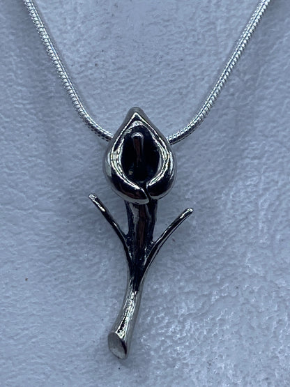 Dije de plata con forma de flor minimalista sobre cadena de plata, vista frontal