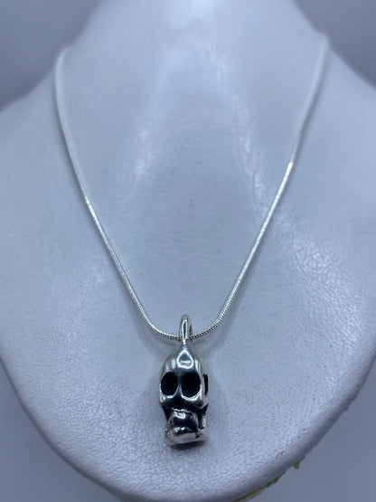 Vista frontal del dije calavera minimalista en plata pulida