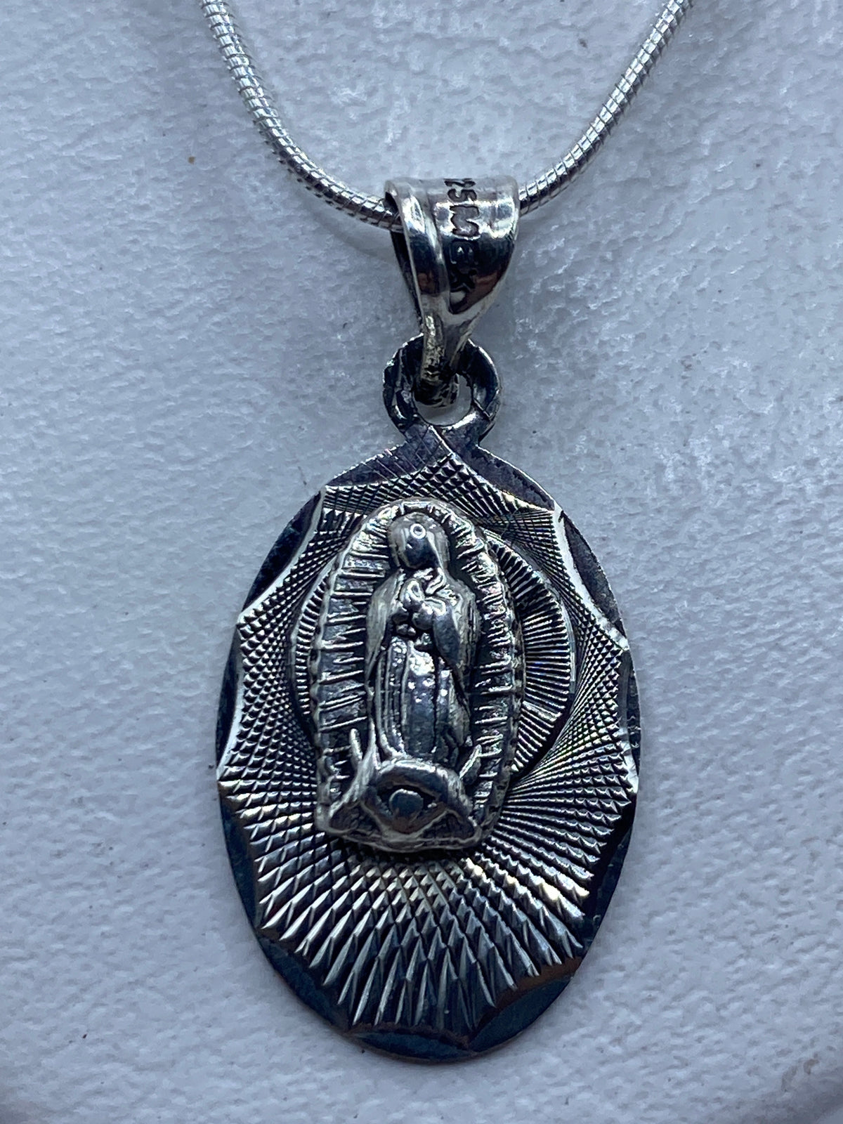 Dije de plata .925 con imagen de Virgen de Guadalupe en relieve, colgante sobre cadena de plata