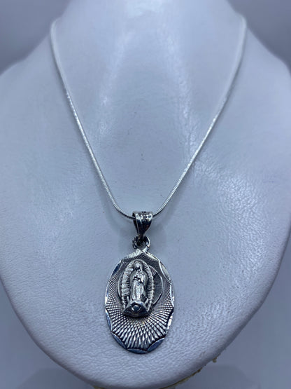 Detalle frontal del dije devocional mostrando la Virgen de Guadalupe y el halo radiante