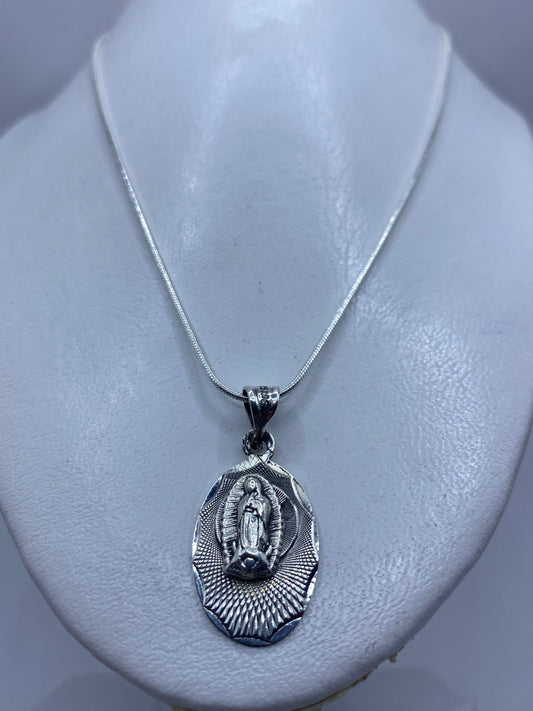 Detalle frontal del dije devocional mostrando la Virgen de Guadalupe y el halo radiante