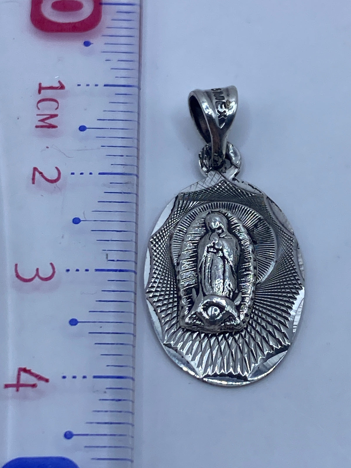 Dije de plata sobre fondo gris mostrando el Quinto .925 en la argolla