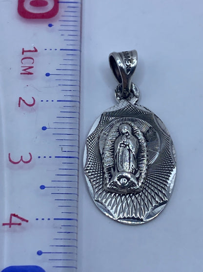 Dije de plata sobre fondo gris mostrando el Quinto .925 en la argolla