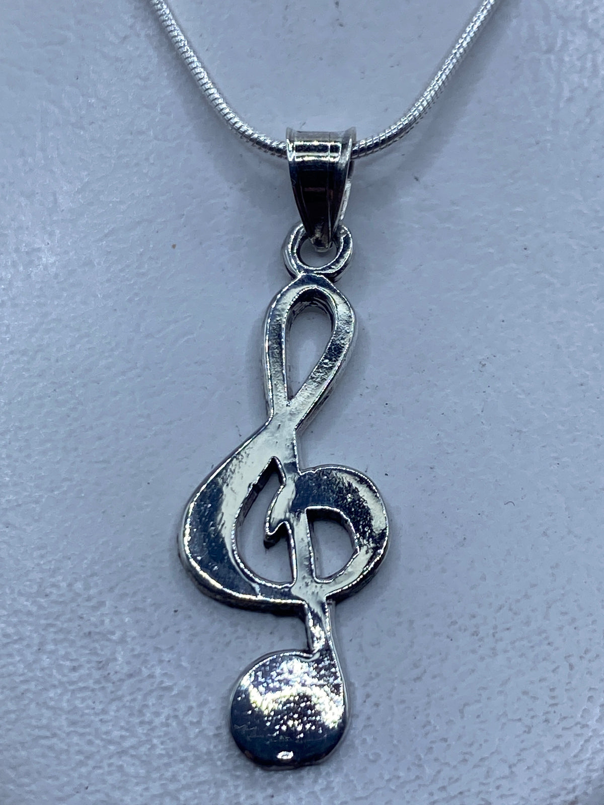 Dije de plata .925 con diseño de clave musical en cadena de plata, detalle frontal