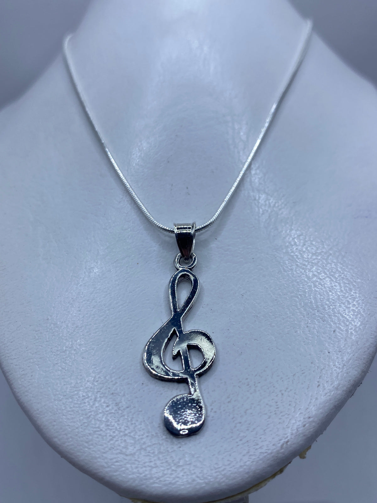 Clave musical de plata sobre piel, mostrando el tamaño real de 4.3 cm