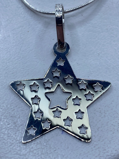 Dije de plata calado en forma de estrella con estrellas pequeñas, colgando de una cadena de plata