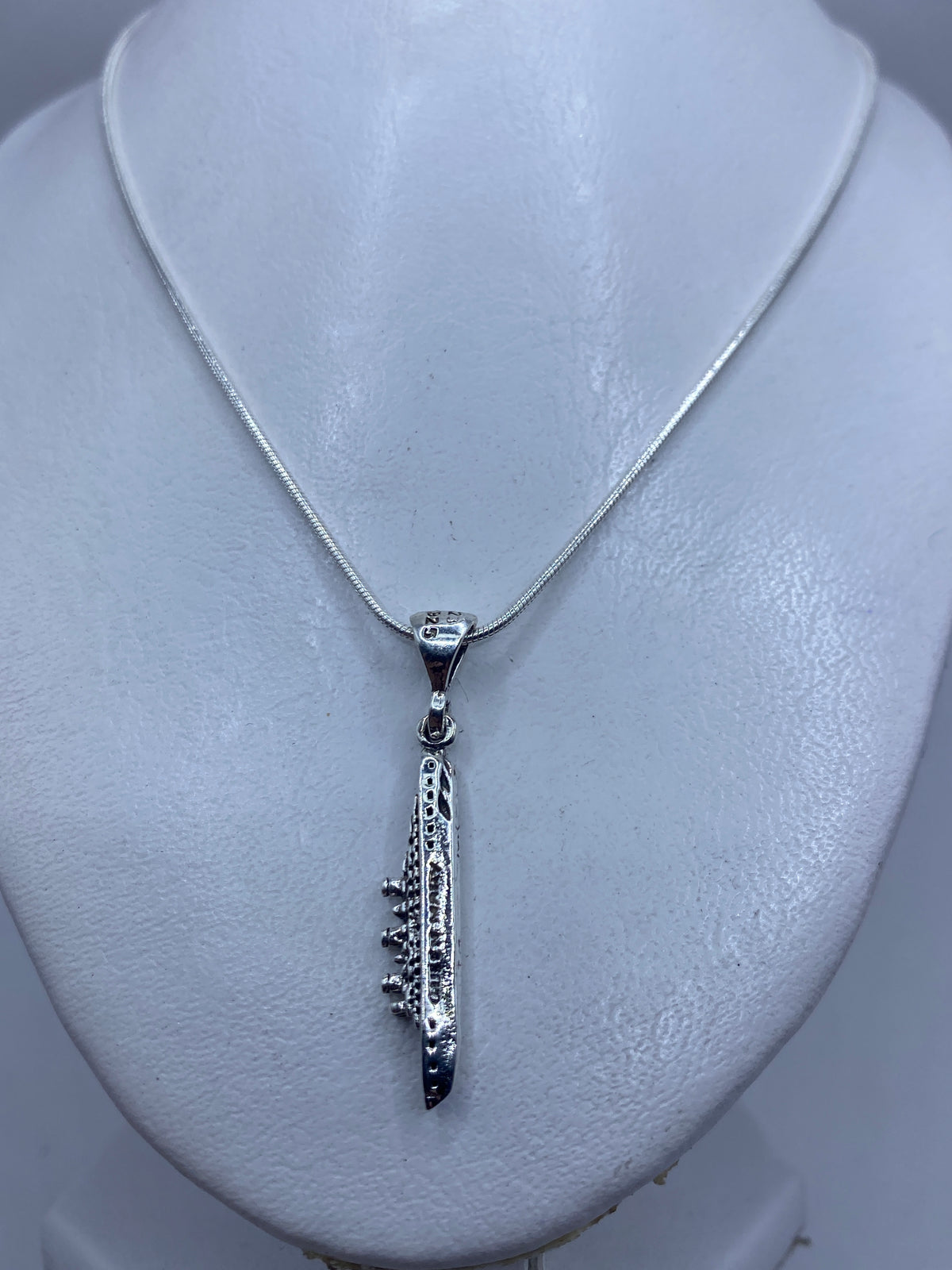 Detalle lateral del dije minimalista con la ansa de sujeción en plata