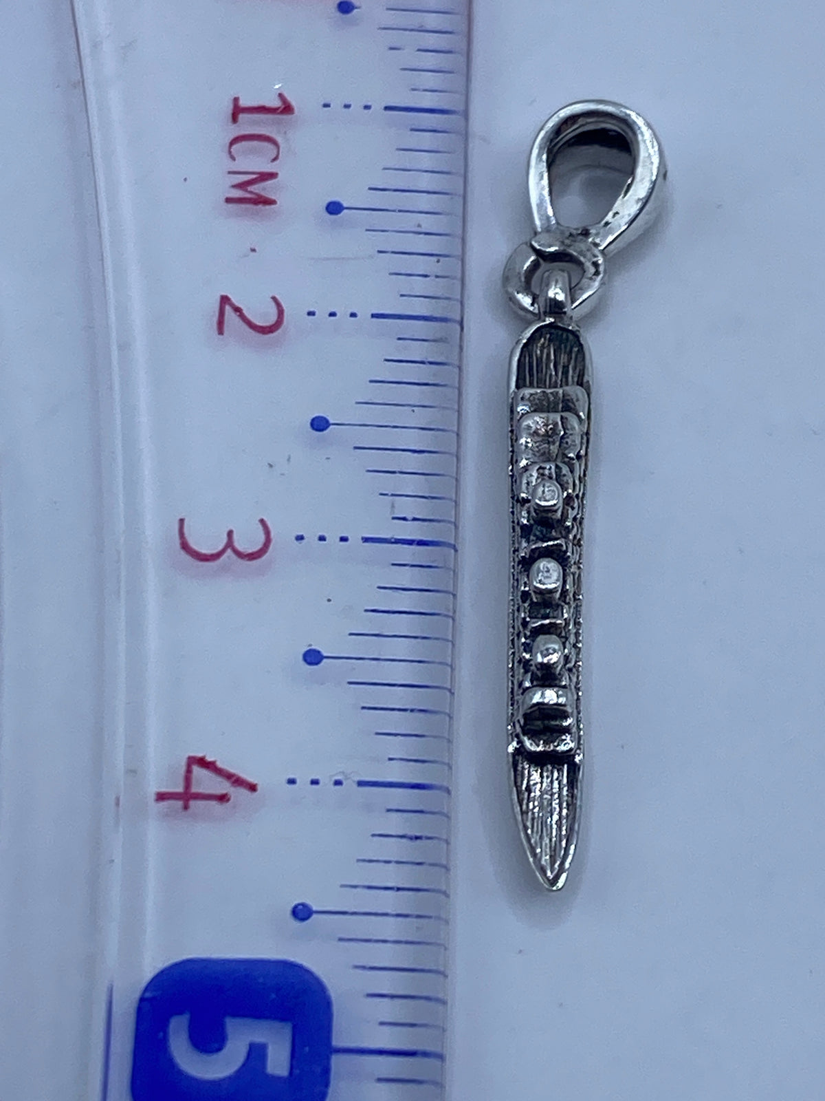 Dije sobre fondo blanco con medida en regla métrica, mostrando los 4.3 cm de largo