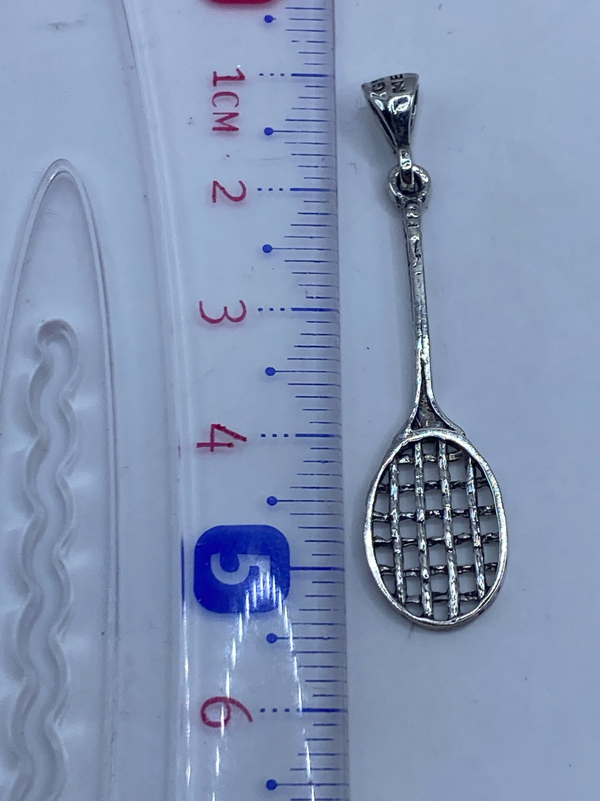 Dije de plata de raqueta de tenis pesando 1.4 gramos en balanza de precisión