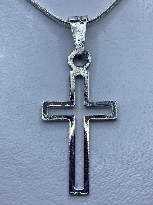 Cruz de plata calada 4.4 cm colgada en cadena fina de plata, sobre piel