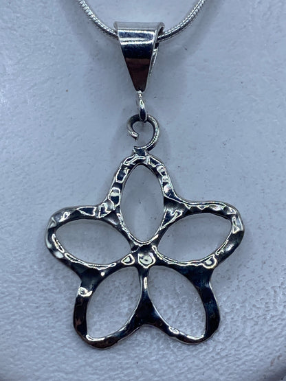 Dije de plata calado en forma de flor de cuatro pétalos sobre cadena de plata