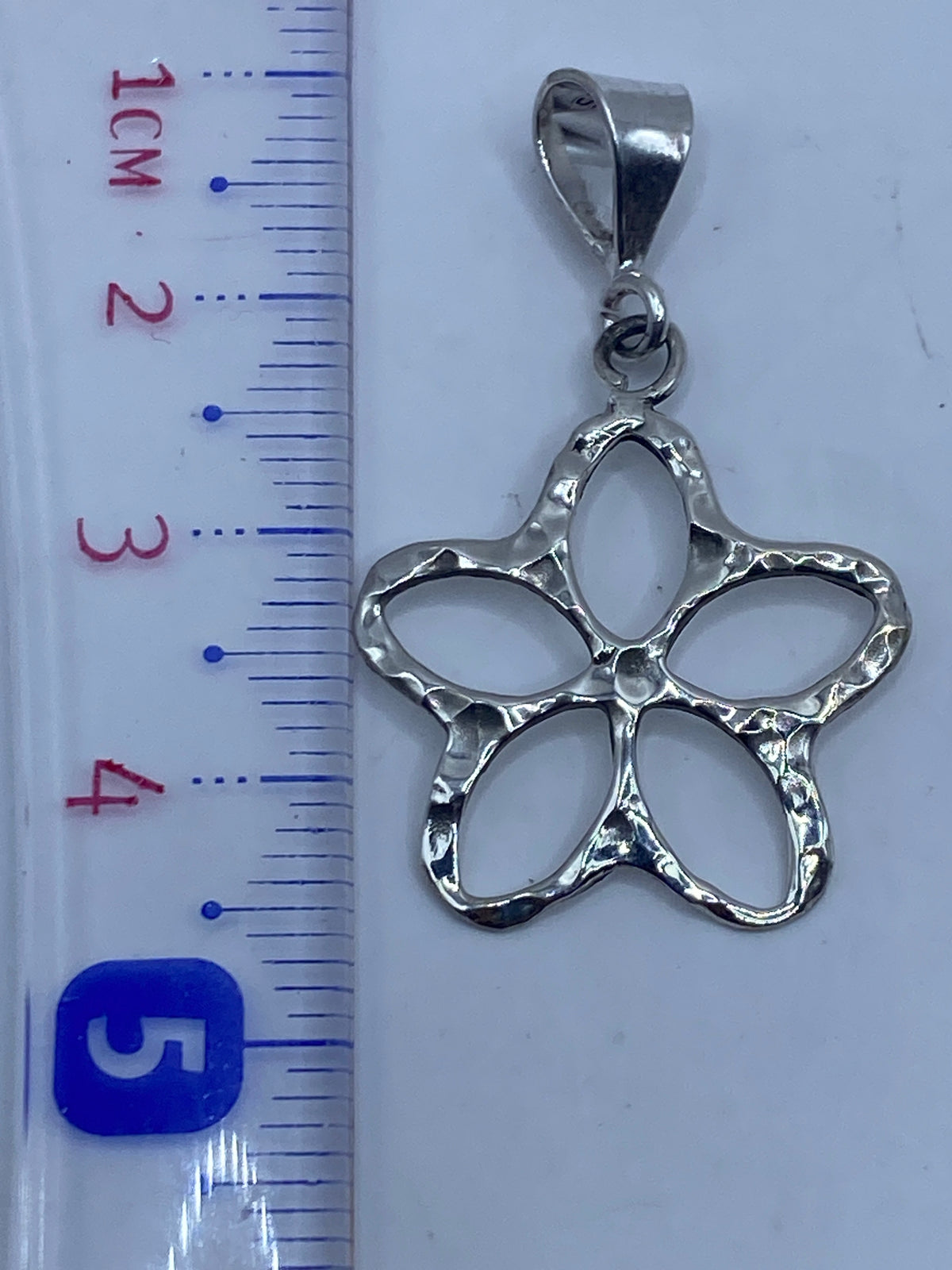 Dije de plata floral sobre fondo blanco mostrando el Quinto .925