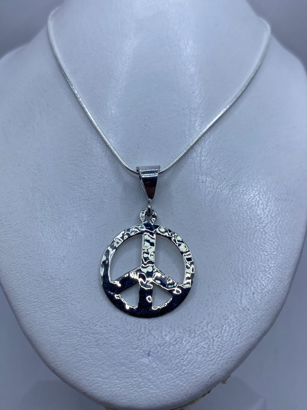 Dije de paz de plata pulida — detalle del acabado minimalista