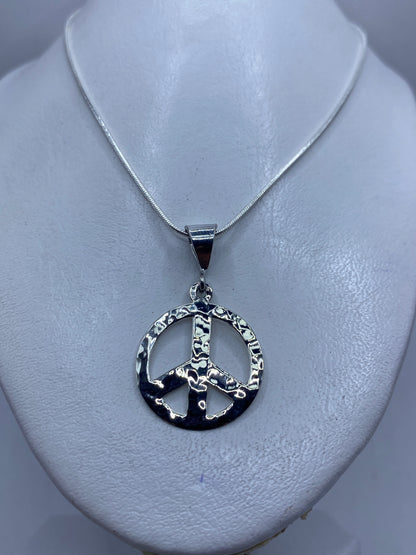 Dije de paz de plata pulida — detalle del acabado minimalista