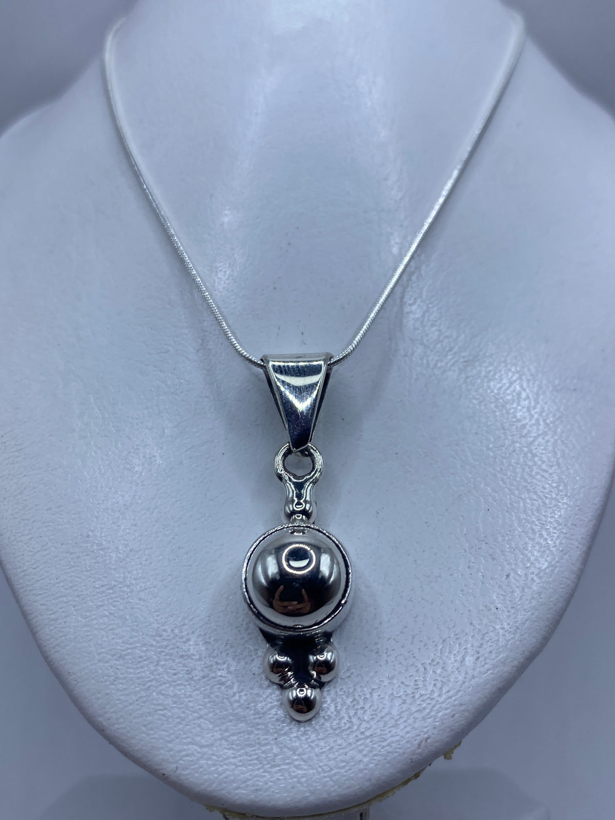 Esfera minimalista de plata contra fondo blanco mostrando el brillo del pulido