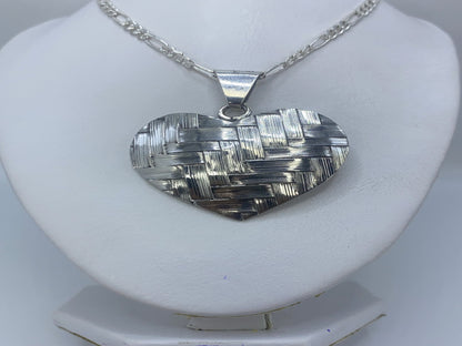 Detalle del relieve en repujado del dije corazón, mostrando el trabajo artesanal