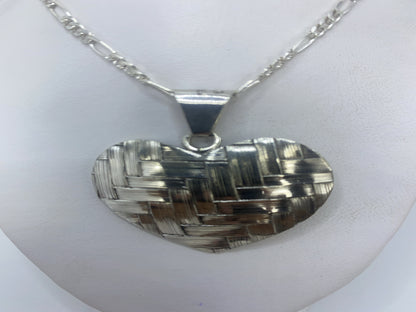 Dije de plata corazón sobre piel blanca, tamaño compacto cerca del escote