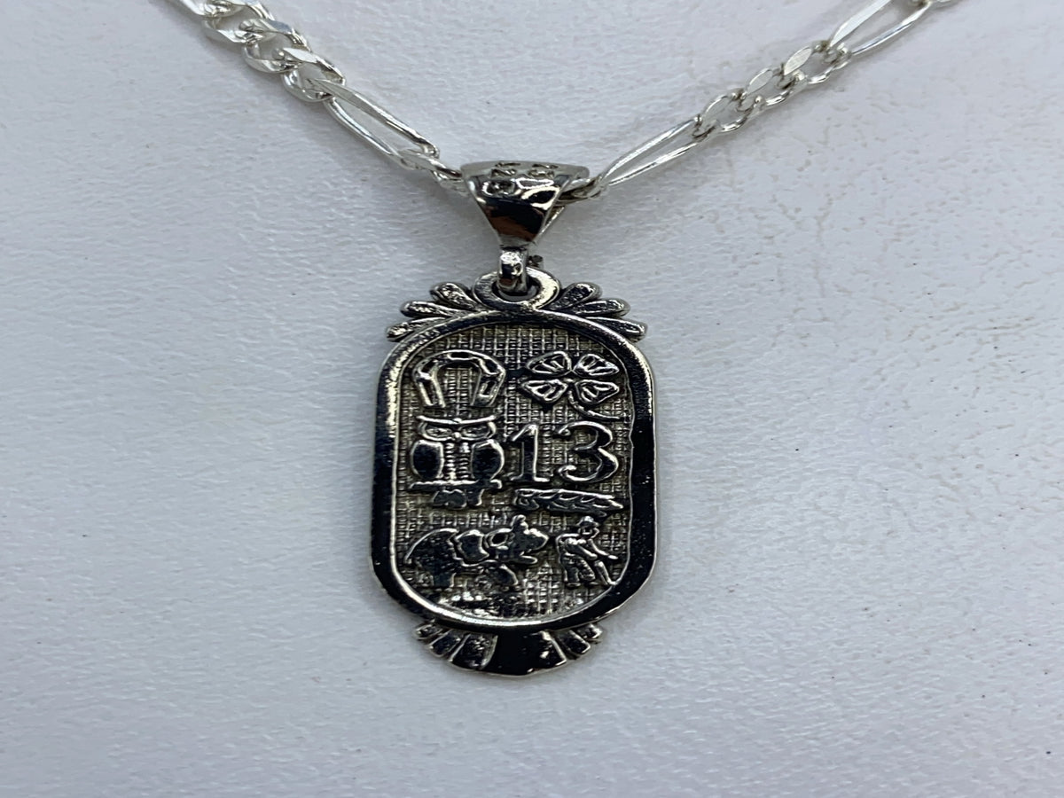 Dije de plata repujado con símbolos prehispánicos aztecas en la mano