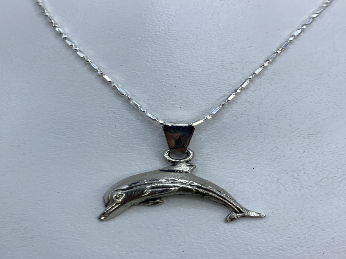 Dije de plata .925 con forma de delfín grabado en relieve, colgando de cadena plateada