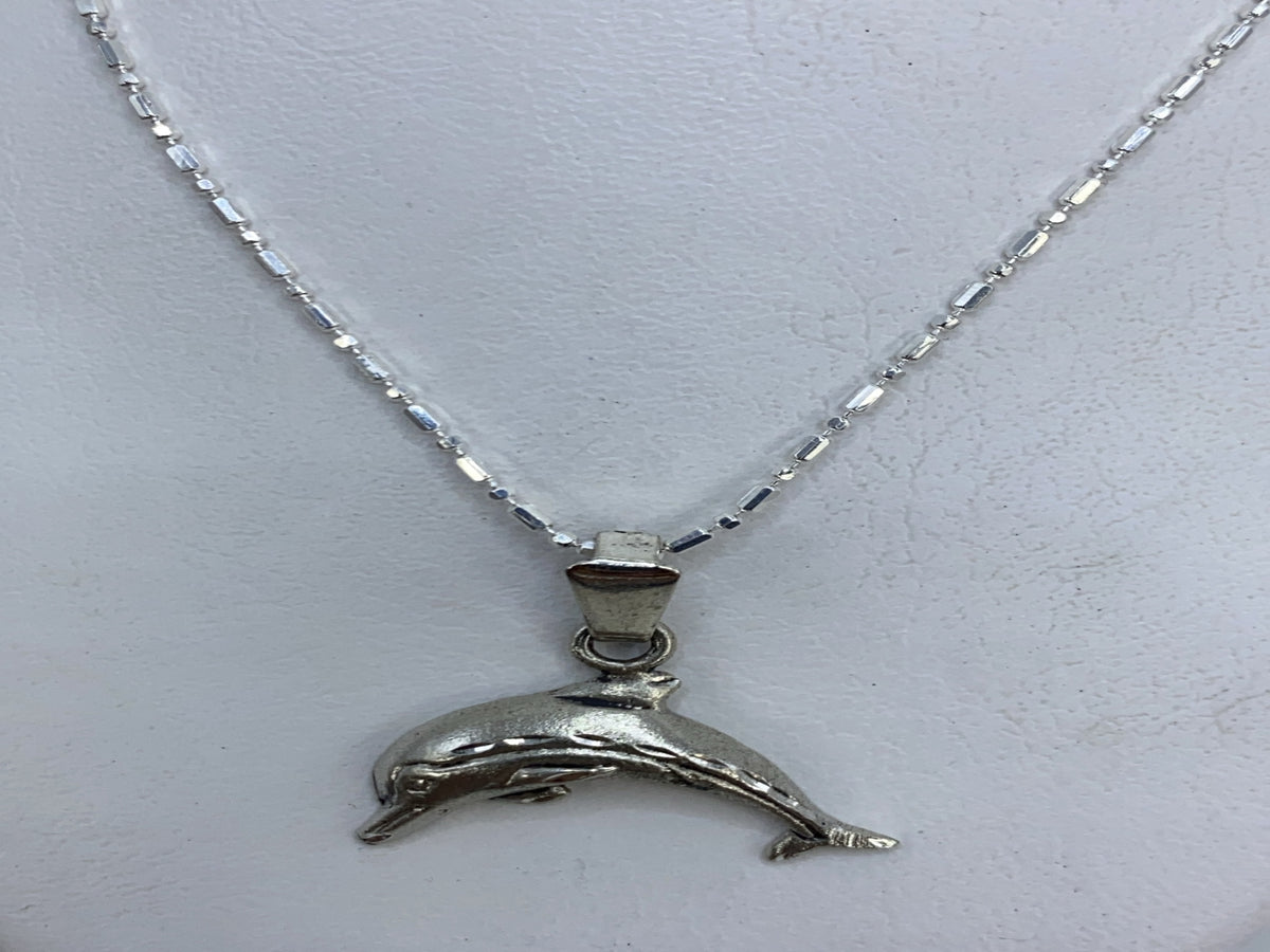 Detalle del delfín en plata mostrando el grabado del cuerpo y la aleta