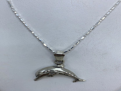 Detalle del delfín en plata mostrando el grabado del cuerpo y la aleta