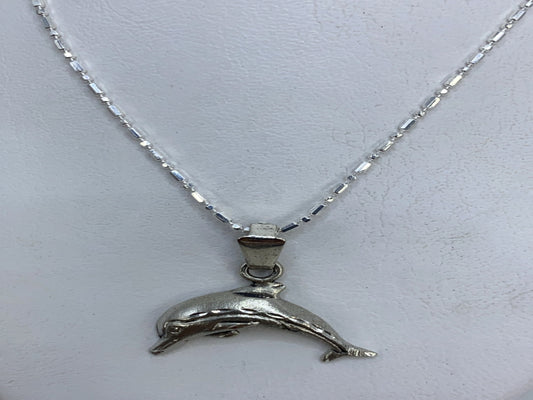 Detalle del delfín en plata mostrando el grabado del cuerpo y la aleta
