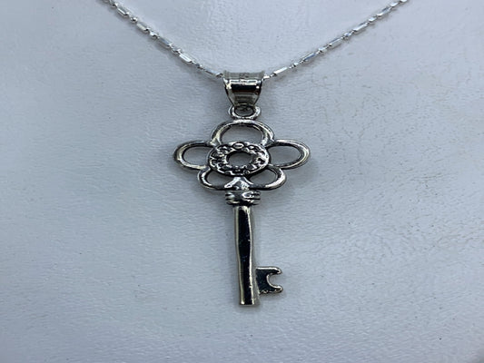 Dije de plata calado en forma de llave floral, largo 4 cm, sobre fondo blanco