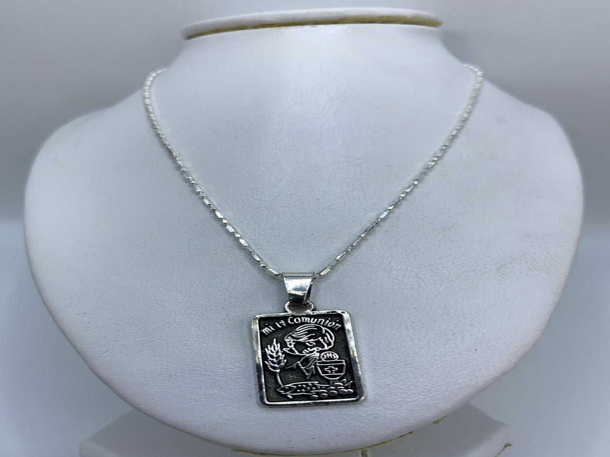 Dije de comunión en plata colocado sobre collar de eslabones