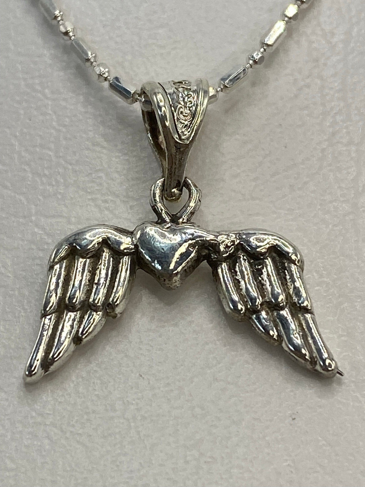 Dije de plata .925 con alas de ángel y corazón en relieve, repujado a mano