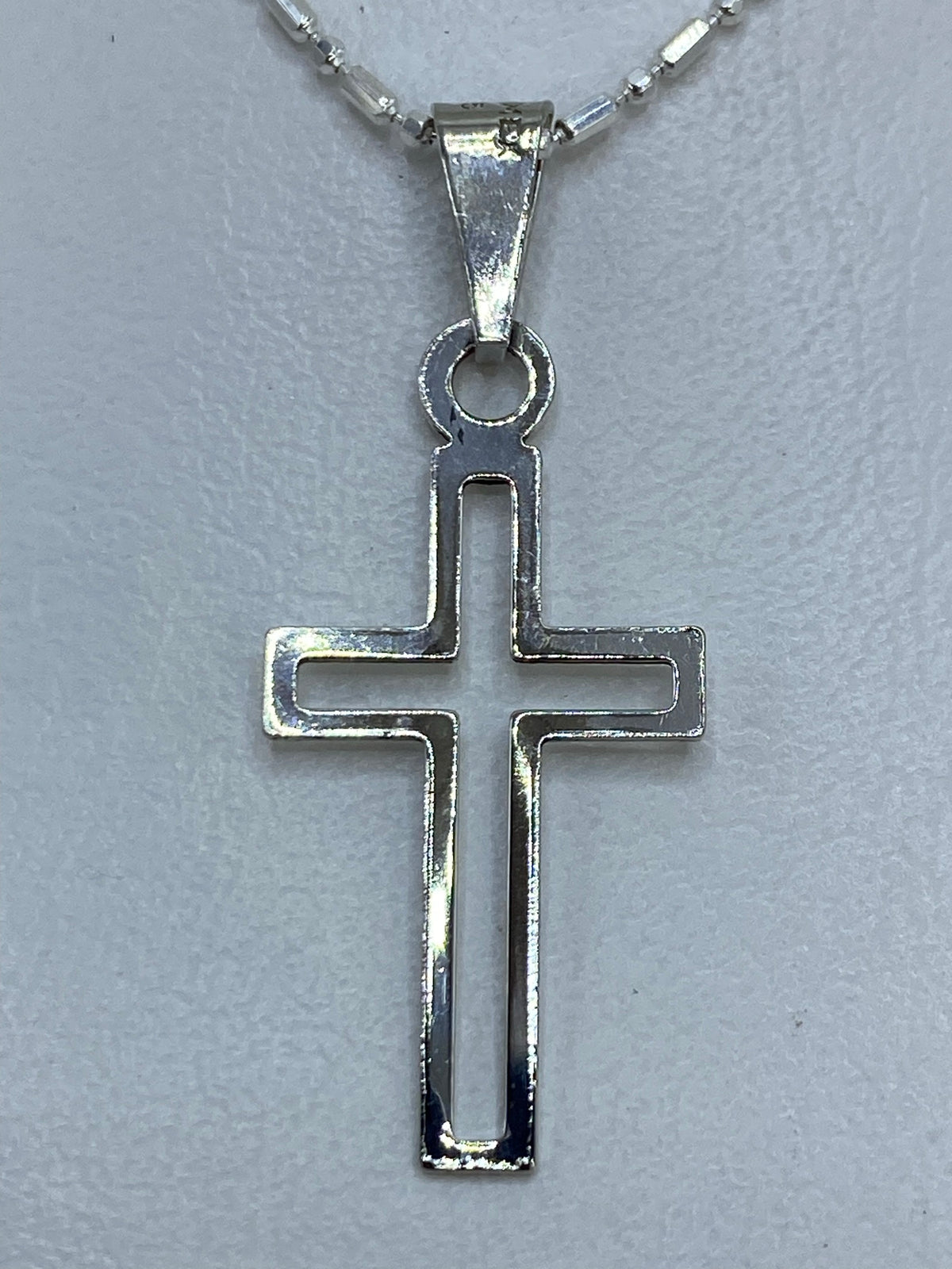 Dije cruz de plata .925 calado minimalista en la mano