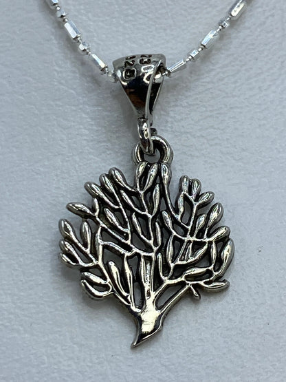 Dije de hoja de plata con corte calado colgando de cadena de bolitas
