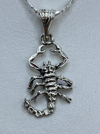Dije de plata .925 con escorpión en calado, 2 cm de largo, sobre fondo gris