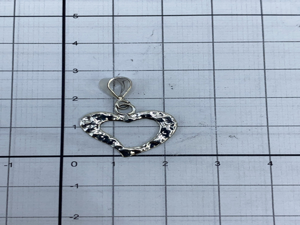 Dije de corazón al lado de regla métrica, midiendo 2 cm de largo