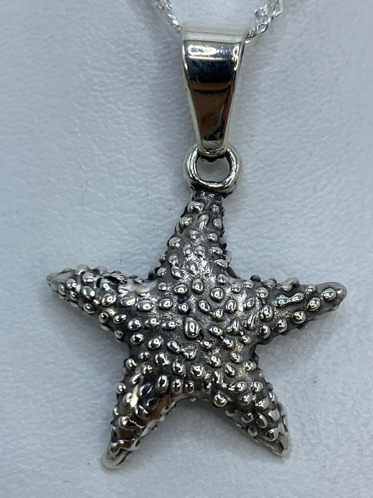 Dije de estrella de mar de 3 cm en plata .925 sobre regla de centímetros