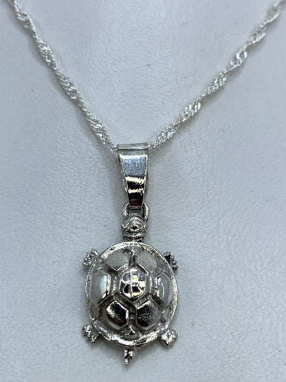 Detalle frontal del dije tortuga mostrando el caparazón hexagonal y la cabeza trabajada en plata .925