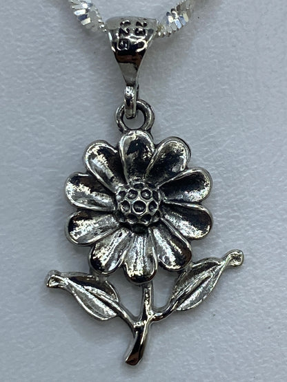 Dije flor con dos hojas en plata de Taxco sobre escala de medidas