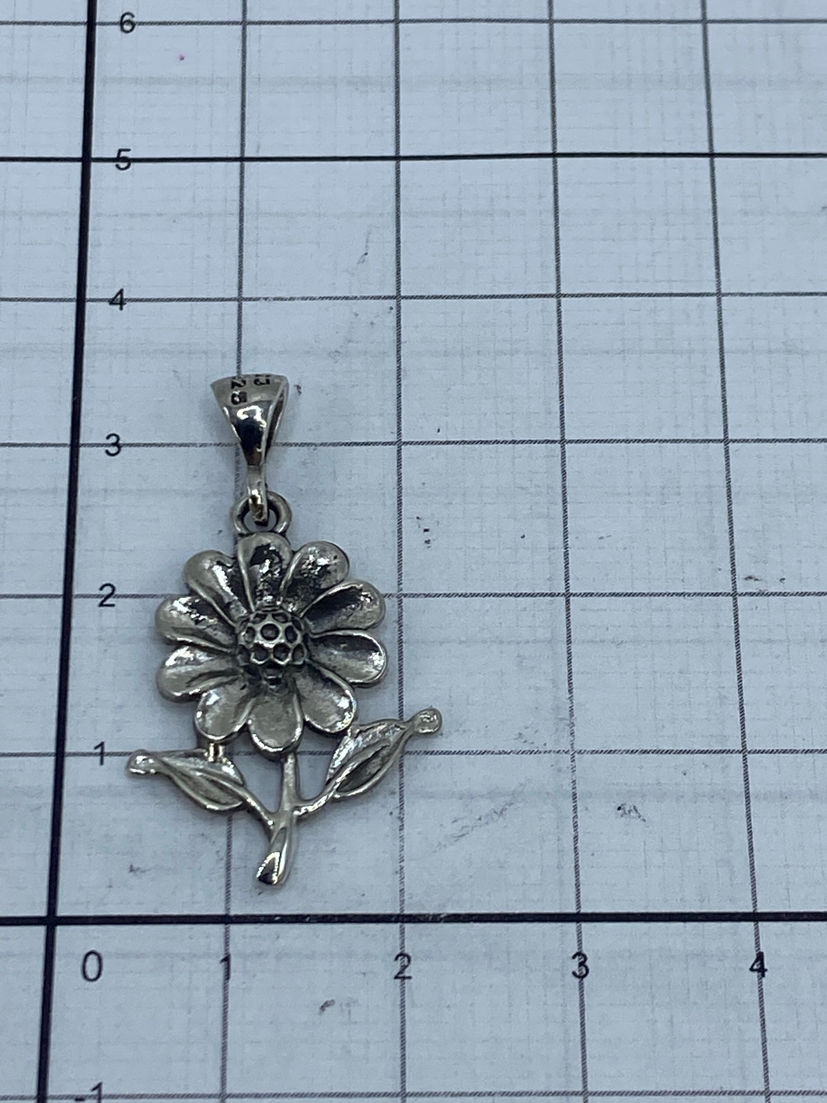 Dije flor de plata vista de frente mostrando textura del repujado