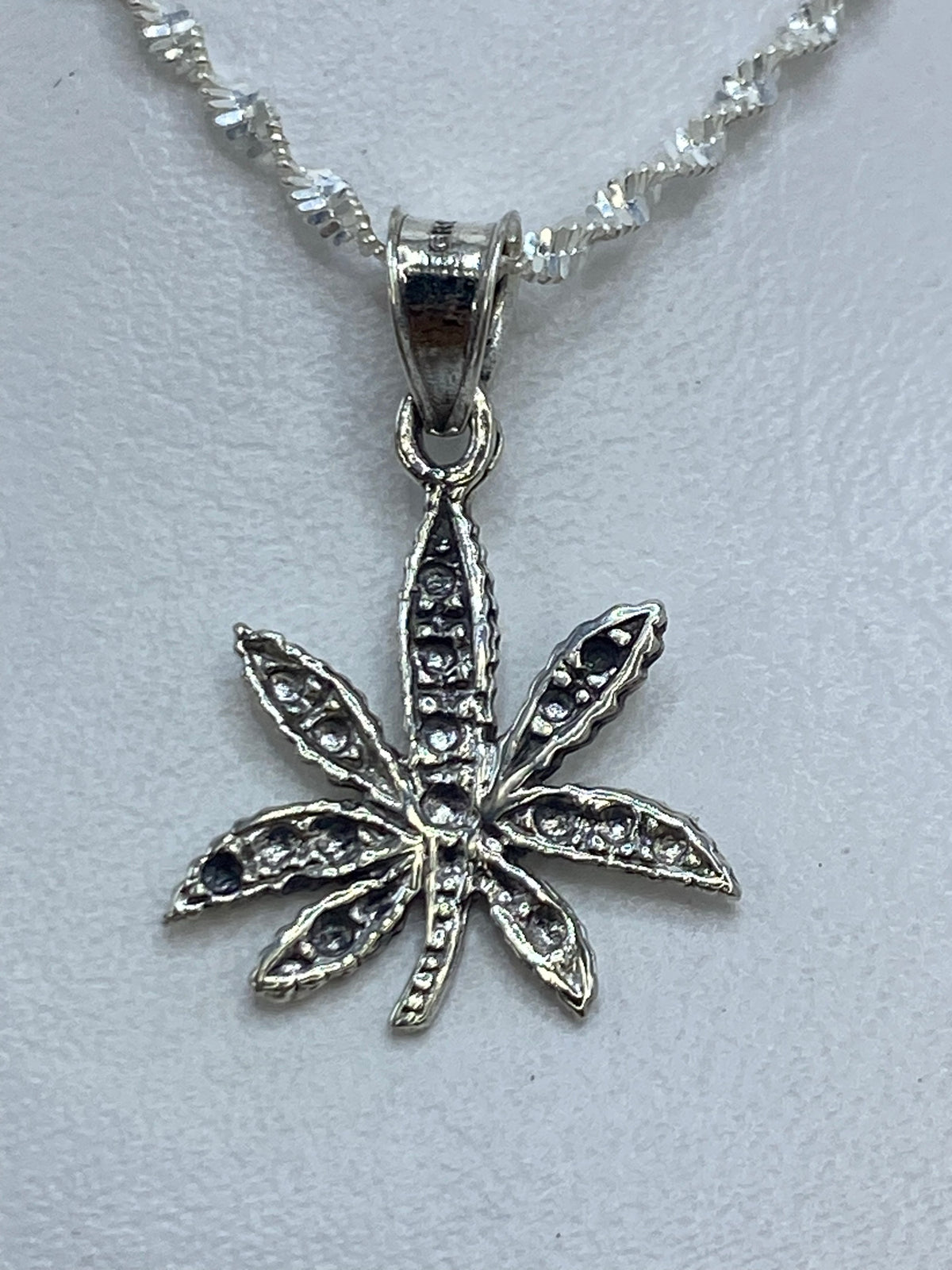 Dije de plata ocho pétalos de 3 cm de largo sobre cadena plateada