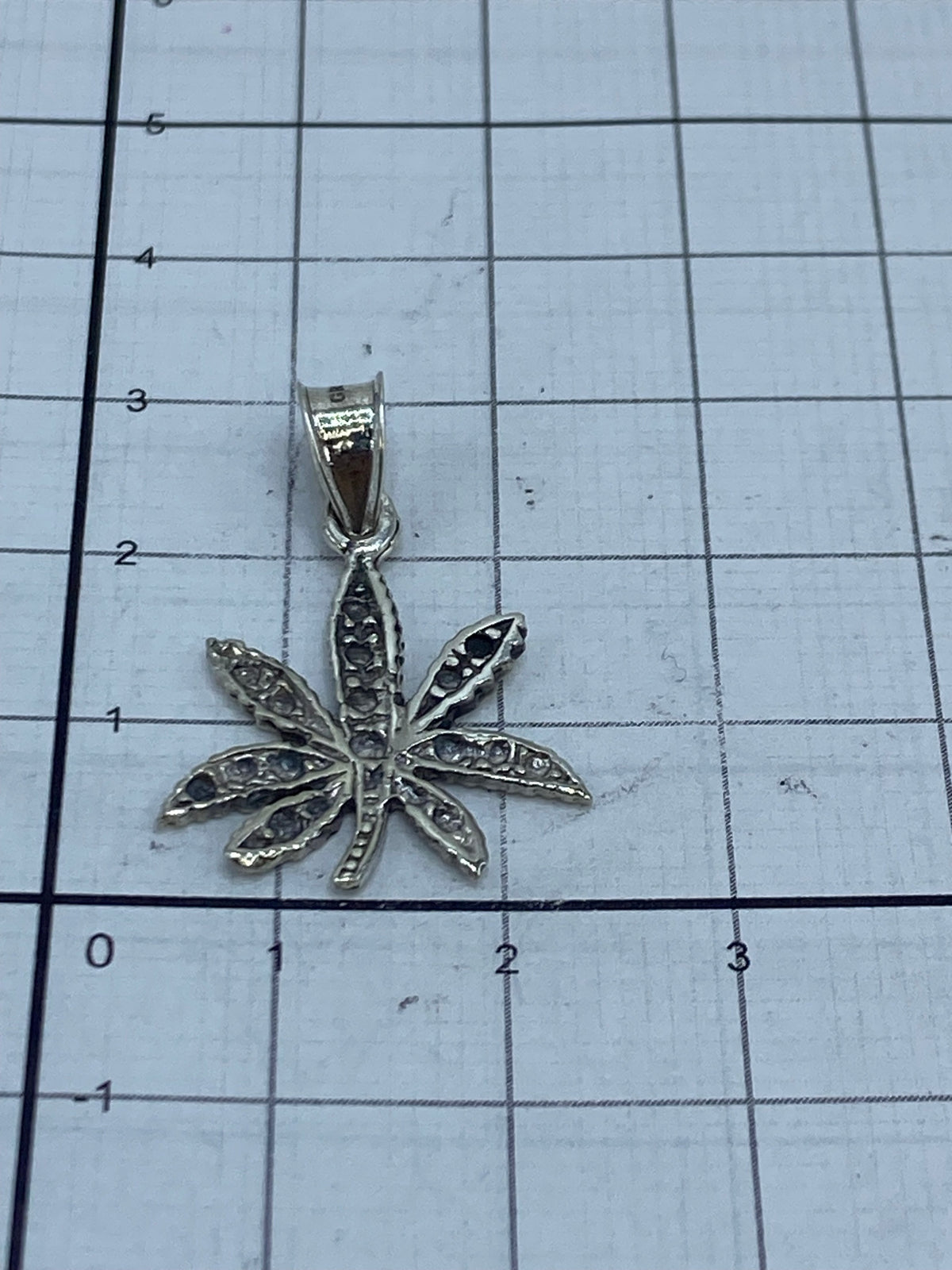 Dije de plata con marca del Quinto 925 junto a regla de medición