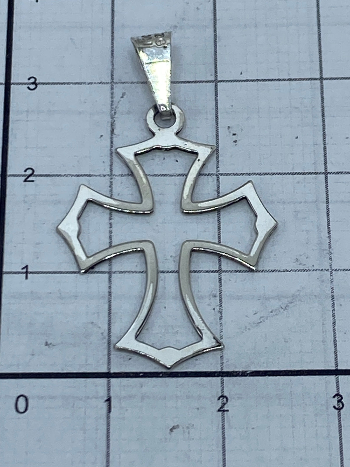 Dije cruz de plata en escala comparativa mostrando 3 cm de largo