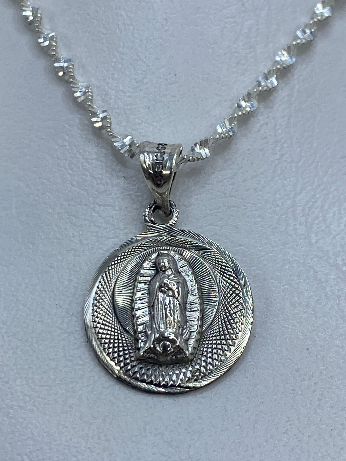 Dije de plata .925 Virgen de Guadalupe con aureola radiante, largo 2 cm, colgado de cadena plateada